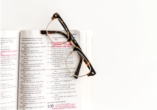 a pair of glasses and an open bible with highlighted bible verses about infertility
