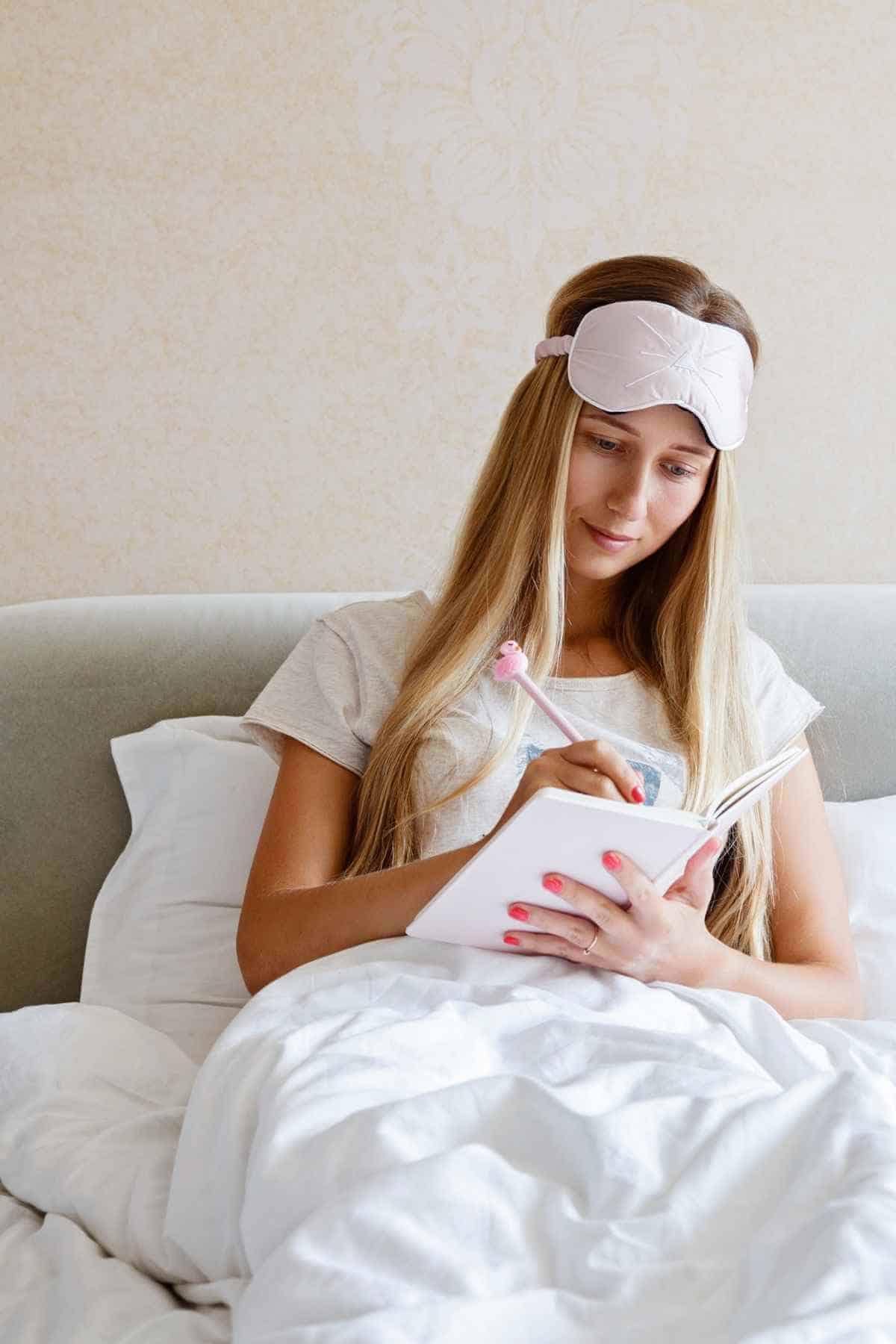 a girl writing in a journal in bed